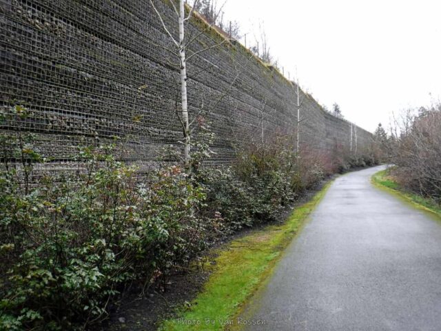 A wall of wire and round stones hold up the freeway